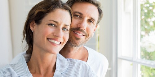 couple smiling in front of window